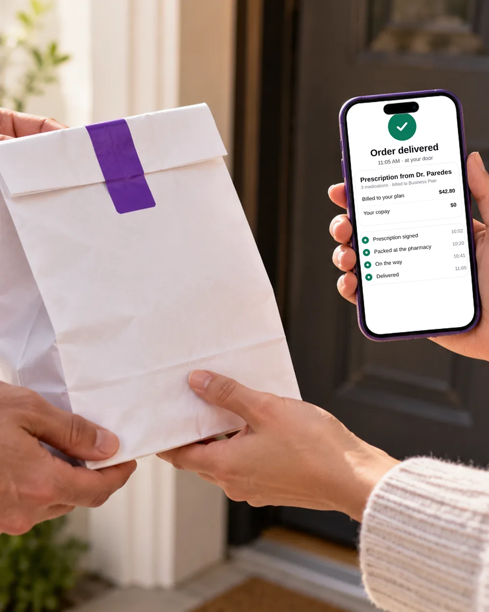A pharmacy bag handed over at a front door while the phone confirms the order was delivered and billed to the plan